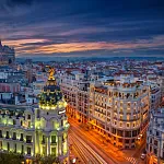 Gran Vía de Madrid al atardecer, con edificios emblemáticos iluminados y ambiente urbano en el centro de la ciudad