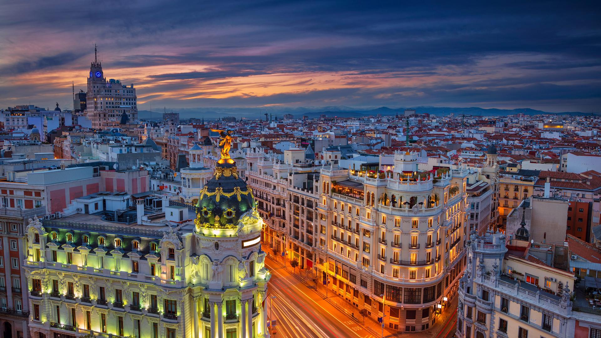 Gran Vía de Madrid al atardecer, con edificios emblemáticos iluminados y ambiente urbano en el centro de la ciudad