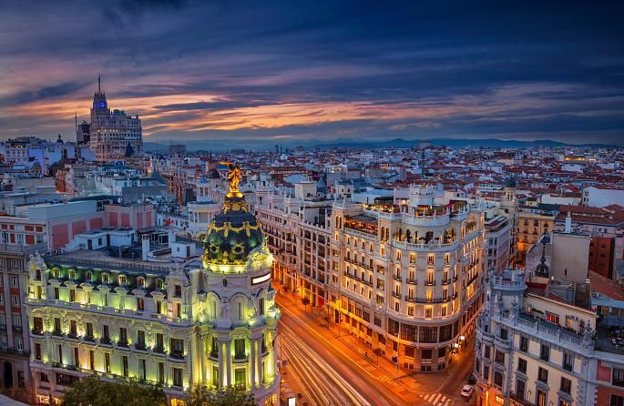 Gran Vía de Madrid al atardecer, con edificios emblemáticos iluminados y ambiente urbano en el centro de la ciudad
